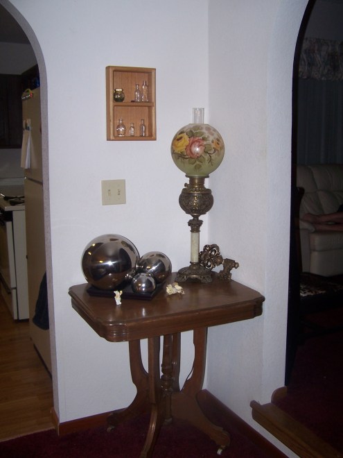 This is the corner of the dining room between the kitchen and the living room.  The antique table and antique lamp are from my grandmother.  The silver balls are modern and I think provide nice contast here.  The little primitive box was one that Tony made when he was in high school.  I think its adorable.  I added antique bottles.  