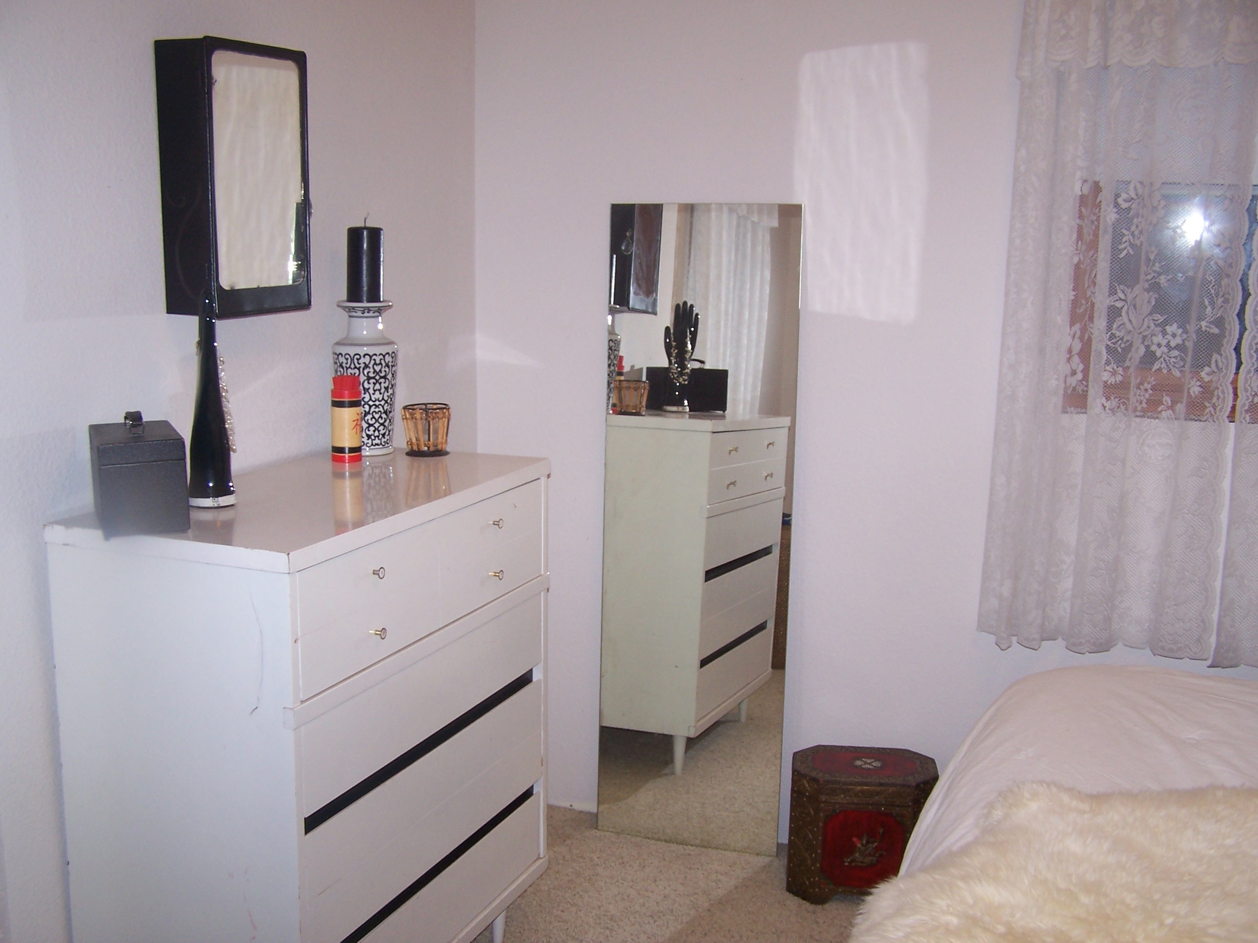 This is the dresser facing the bed. An old full length miror stands against the wall and an Asian keepsake box sits on the floor next to it.The dresser is vintage from when my mom was a little girl. She used the room set and then I did when I was little. The black strips are removable, and flip over to change colors. We painted one side of each black. 