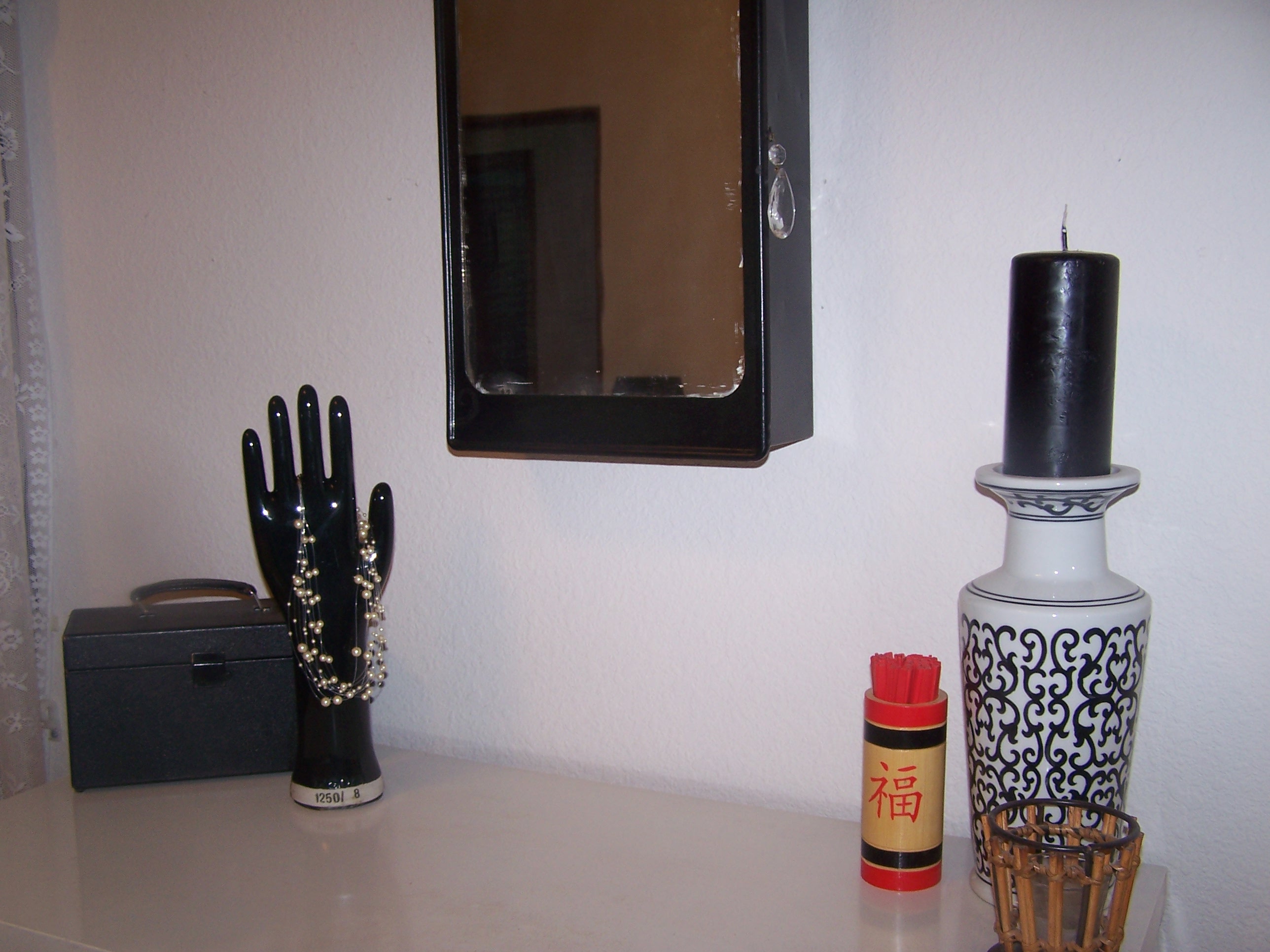 The hand is a vintage glove mold, the box is an old Kodak box, which we keep our momentos in. The mirror is an antique medicine cabinet, which we painted black and added a chendelier crystal for a pull.