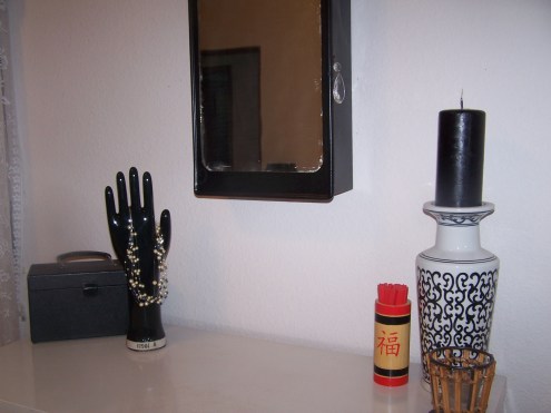 The hand is a vintage glove mold, the box is an old Kodak box, which we keep our momentos in. The mirror is an antique medicine cabinet, which we painted black and added a chendelier crystal for a pull.