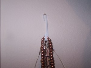 Here is a close-up of the hook I used.  It is actually a hook that fits over a door, so one end is flat, which I use to hold multiple necklaces.  The other end is curved, but I twisted it with pliers to hang agianst a wall.  So simple I even did it myself.
